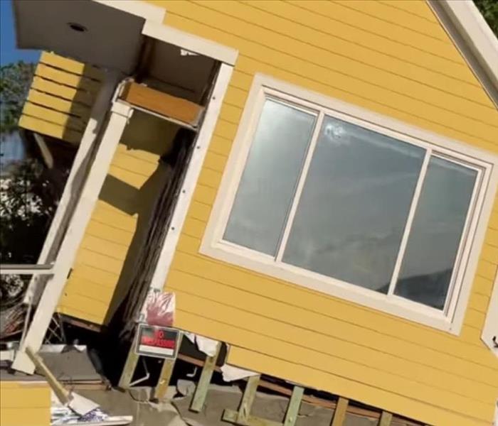 A yellow house is damaged from an intense storm 